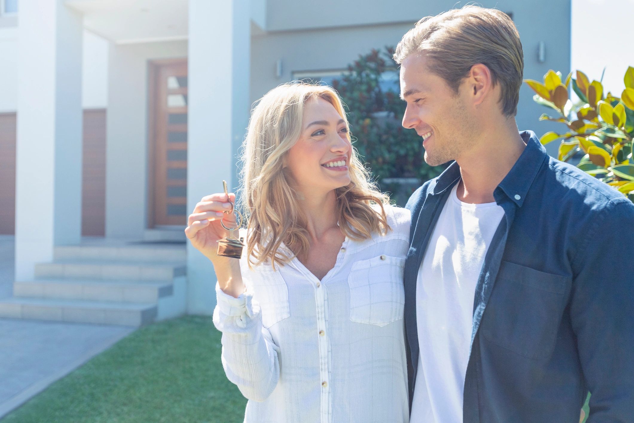 Happy couple holding keys in front of their new home