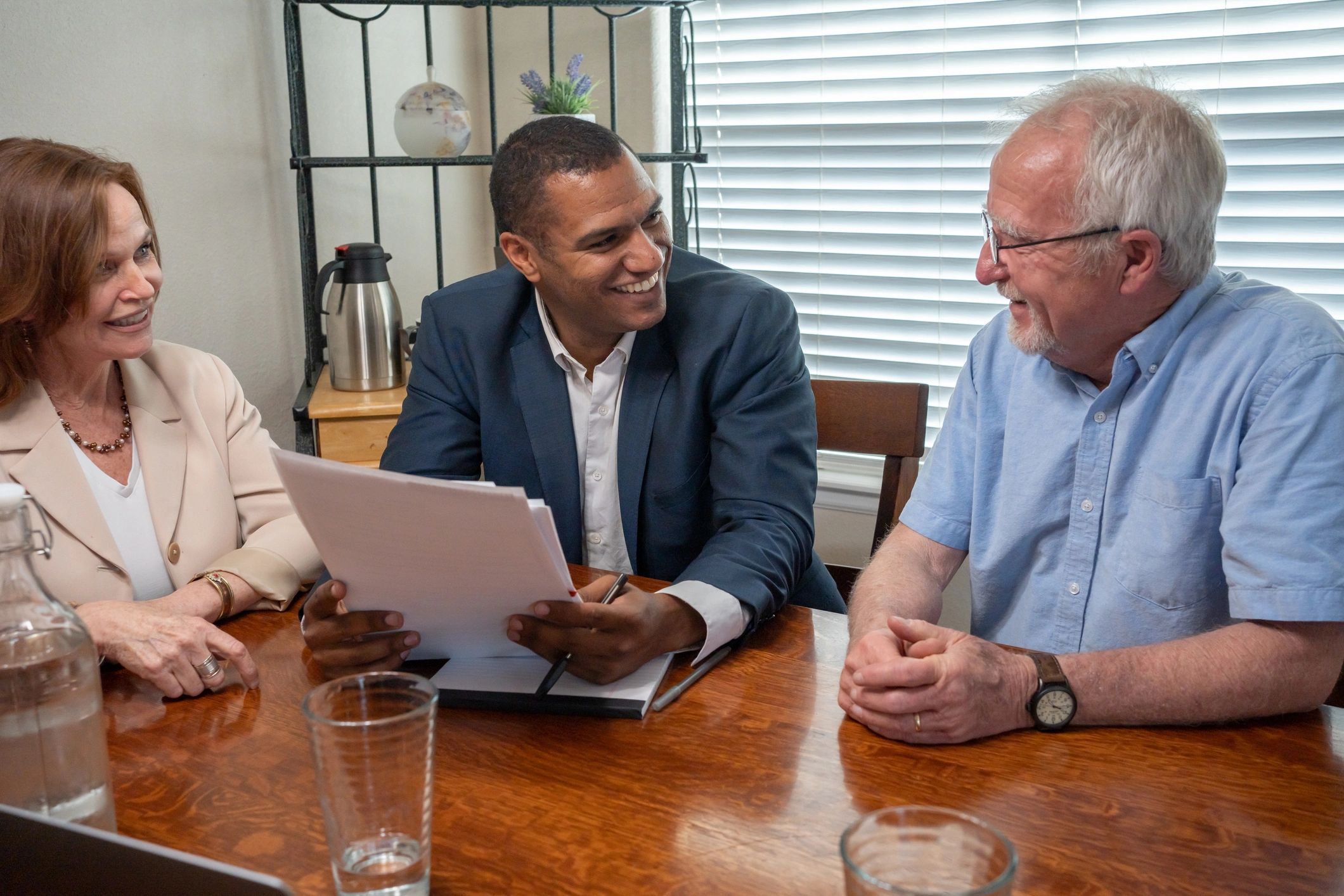 Mortgage advisor reviewing documents with clients at a kitchen table